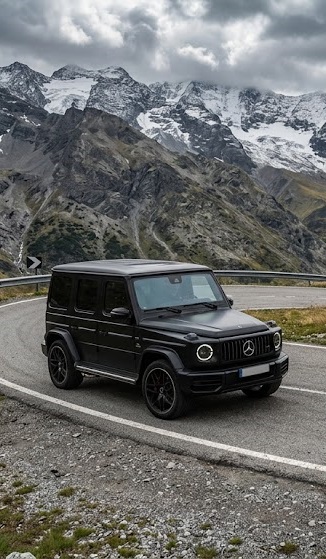 Mercedes-AMG G63 preto em estrada de montanha com picos nevados ao fundo